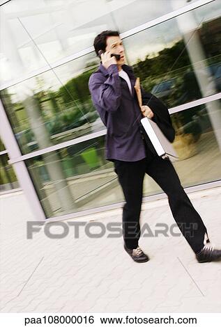 Man walking with cell phone, outdoors View Large Photo Image Stock Photograph - Man walking with cell phone, outdoors. Fotosearch