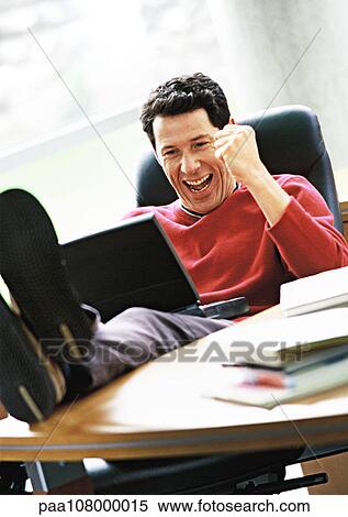 Man with laptop on lap and feet on desk, smiling View Large Photo Image Stock Photography - Man with laptop on lap and feet on desk, smiling. Fotosearch