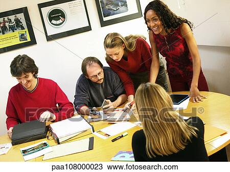 People sitting at and leaning over table in conference room, tilt. View Large Photo Image Stock Image - People sitting at and leaning over table in conference room, tilt.. Fotosearch