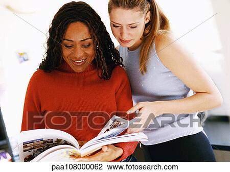 Two women looking at catalog View Large Photo Image Stock Image - Two women looking at catalog. Fotosearch
