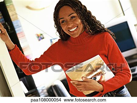 Woman holding catalog in office, smiling View Large Photo Image Picture - Woman holding catalog in office, smiling. Fotosearch