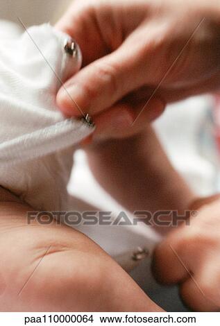 Adult closing baby's clothing between legs, close-up View Large Photo Image Picture - Adult closing baby's clothing between legs, close-up. Fotosearch