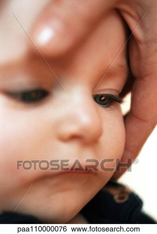 Adult hand around baby's face, close-up View Large Photo Image Stock Photograph - Adult hand around baby's face, close-up. Fotosearch