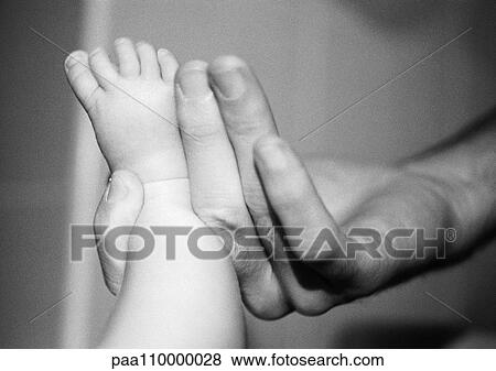 Adult hand holding baby's foot, close-up, b&w View Large Photo Image Stock Photo - Adult hand holding baby's foot, close-up, b&w. Fotosearch