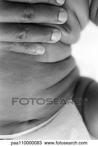 Stock Image - Adult hand on baby's chest, close-up, b&w. Fotosearch