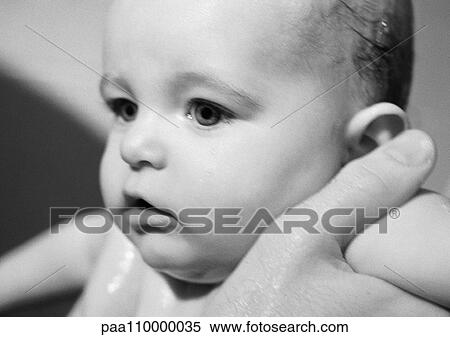 Stock Photography - Adult's hands holding baby under arms, close-up, b&w. Fotosearch