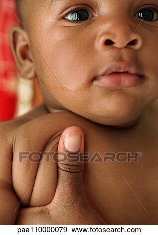 Stock Photo - Baby being held by adult hand, close-up. Fotosearch