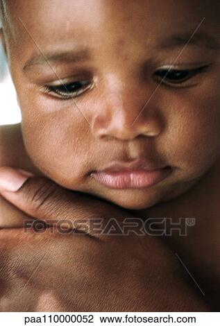 Stock Image - Baby with adult's hand on chest, close-up. Fotosearch