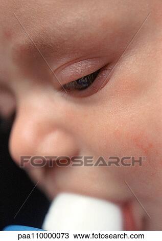 Stock Image - Baby with bottle in mouth, extreme close-up. Fotosearch