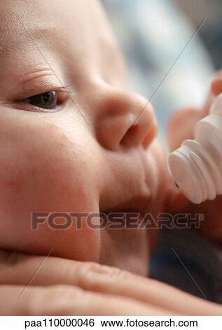 Stock Photograph - Baby's face and end of vitamin dropper, close-up. Fotosearch