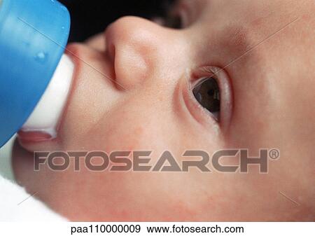 Stock Photo - Baby's face, drinking from bottle, close-up. Fotosearch