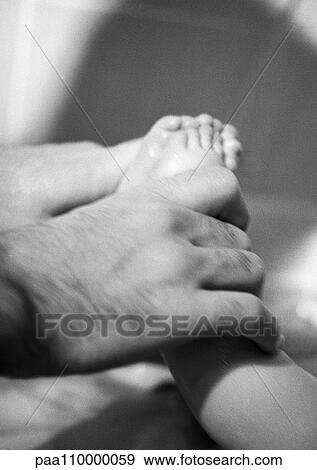 Father's hand holding baby's feet, close-up, b&w View Large Photo Image Stock Photo - Father's hand holding baby's feet, close-up, b&w. Fotosearch