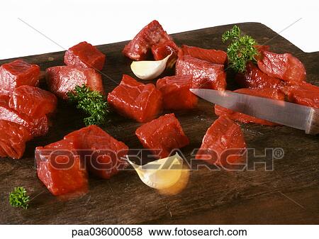 Cubed beef on cutting board with knife, cloves of garlic and sprigs of parsley, close-up View Large Photo Image Stock Photo - Cubed beef on cutting board with knife, cloves of garlic and sprigs of parsley, close-up. Fotosearch