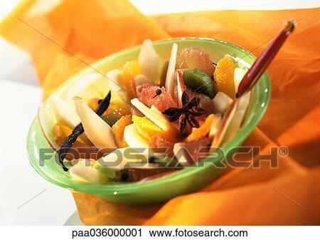 Stock Image - Fruit salad in bowl on orange fabric, close-up. Fotosearch