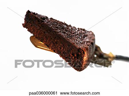 Stock Image - Piece of chocolate cake on cake server, close-up, white background. Fotosearch
