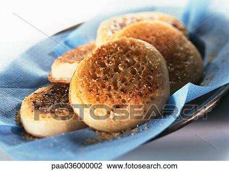 Stock Image - Pile of crumpets on blue paper, close-up. Fotosearch