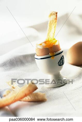 Soft-boiled egg in eggcup with eggyolk dripping over side and bread crusts View Large Photo Image Picture - Soft-boiled egg in eggcup with eggyolk dripping over side and bread crusts. Fotosearch