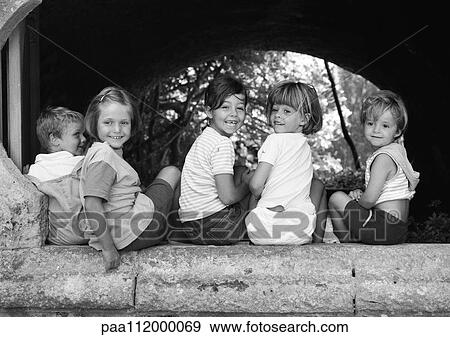 Stock Photo - Five children sitting under an arch, b&w. Fotosearch