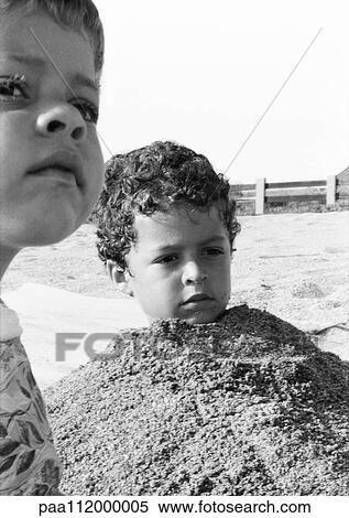 Girl and boy outside, one buried in sand, b&w View Large Photo Image Stock Photography - Girl and boy outside, one buried in sand, b&w. Fotosearch