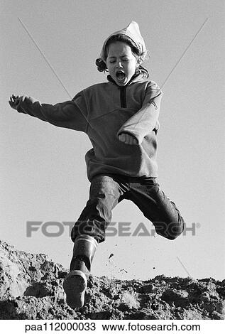 Stock Image - Girl jumping, low angle view, b&w. Fotosearch