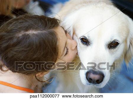 Stock Photo - Girl kissing dog, elevated view. Fotosearch