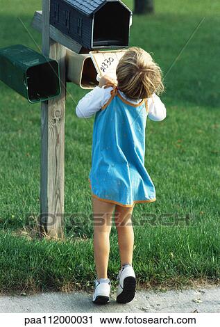 Stock Image - Girl looking into mailbox, rear view. Fotosearch