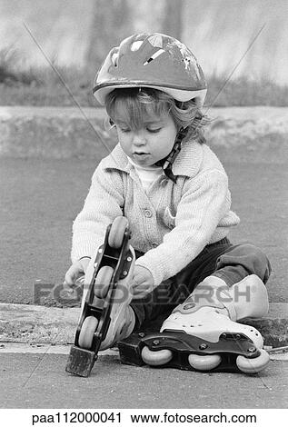 Girl putting on in-line skates, sitting, b&w View Large Photo Image Stock Image - Girl putting on in-line skates, sitting, b&w. Fotosearch
