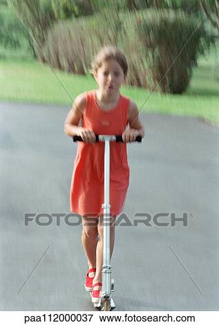 Stock Photo - Girl riding scooter, blurred motion. Fotosearch