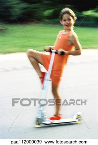 Stock Photo - Girl riding scooter, blurred motion. Fotosearch