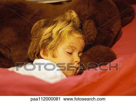 Stock Image - Girl sleeping, head on teddy bear. Fotosearch