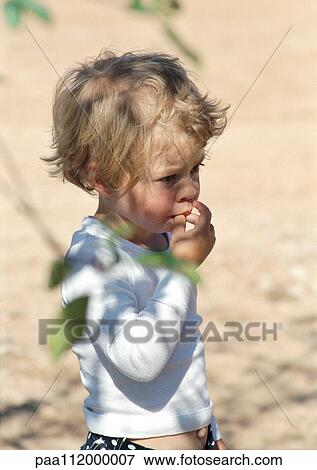 Girl with fingers in mouth, tree leaves in foreground View Large Photo Image Stock Photo - Girl with fingers in mouth, tree leaves in foreground. Fotosearch