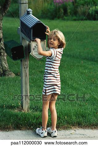 Stock Image - Girl with hand in mailbox, looking into camera. Fotosearch
