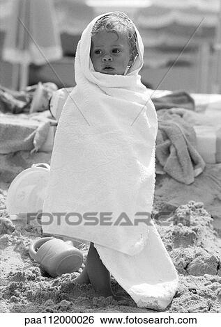 Stock Photograph - Little girl wrapped in towel on beach, b&w. Fotosearch
