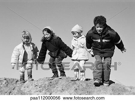 Stock Photograph - Three girls and boy holding hands, preparing to jump, b&w. Fotosearch