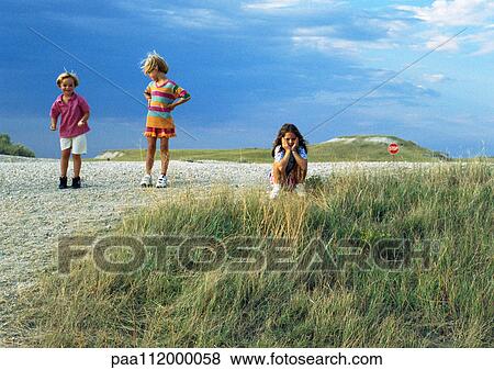 Stock Photo - Three girls outside, one sitting. Fotosearch