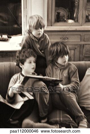 Stock Photograph - Two girls and boy on sofa, b&w. Fotosearch
