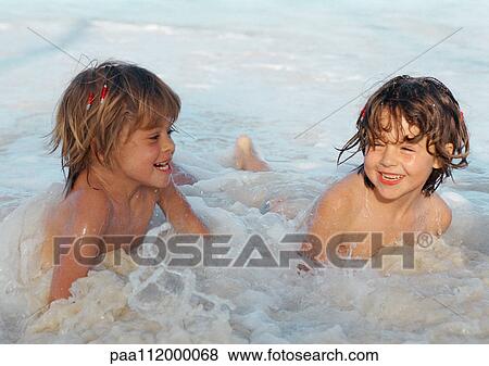 Stock Photo - Two girls playing in the water, smiling. Fotosearch