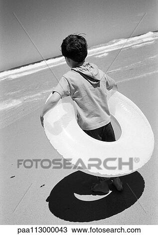 Child in inner tube standing on the beach. B&W View Large Photo Image Stock Image - Child in inner tube standing on the beach. B&W. Fotosearch
