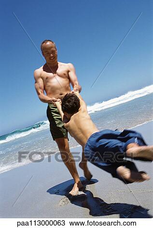 Close-up of man swinging child on the beach. View Large Photo Image Stock Image - Close-up of man swinging child on the beach.. Fotosearch