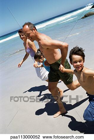 Family running together hand-in-hand on the beach. View Large Photo Image Stock Image - Family running together hand-in-hand on the beach.. Fotosearch