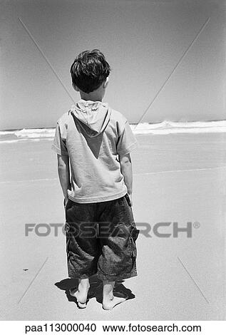 Little boy standing on beach, rear view, ocean in background, B&W View Large Photo Image Stock Image - Little boy standing on beach, rear view, ocean in background, B&W. Fotosearch