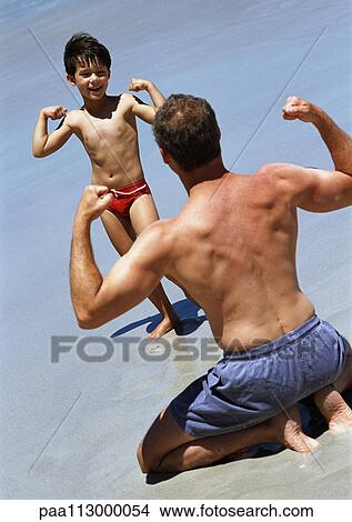 Man and child facing each other, flexing on beach View Large Photo Image Picture - Man and child facing each other, flexing on beach. Fotosearch