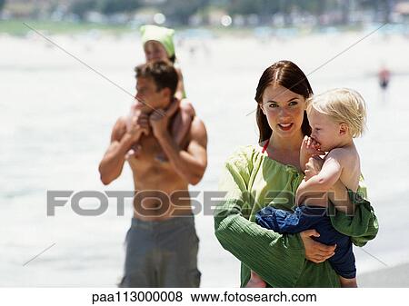Man and woman carrying children on the beach. View Large Photo Image Stock Photo - Man and woman carrying children on the beach.. Fotosearch