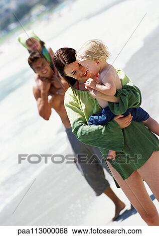 Man and woman holding young children at the beach. View Large Photo Image Stock Photo - Man and woman holding young children at the beach.. Fotosearch