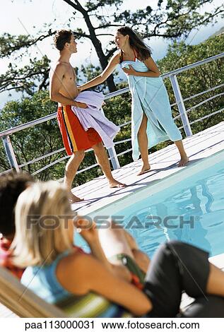 Man and woman sitting, looking at teenagers standing by edge of pool View Large Photo Image Stock Image - Man and woman sitting, looking at teenagers standing by edge of pool. Fotosearch