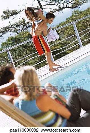 Man and woman sitting, watching teenage boy picking up teenage girl at edge of pool View Large Photo Image Stock Image - Man and woman sitting, watching teenage boy picking up teenage girl at edge of pool. Fotosearch
