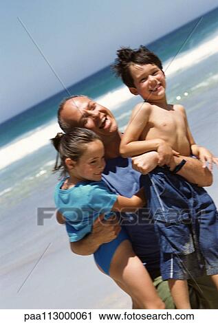 Man carrying two young children at the beach. View Large Photo Image Stock Image - Man carrying two young children at the beach.. Fotosearch