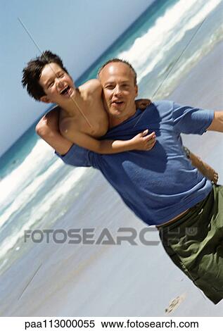 Man carrying young boy on back on the beach. View Large Photo Image Stock Photography - Man carrying young boy on back on the beach.. Fotosearch