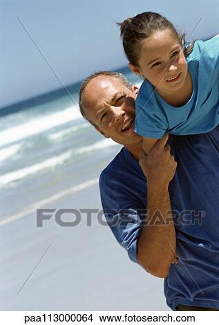Man carrying young girl on shoulder on the beach. View Large Photo Image Picture - Man carrying young girl on shoulder on the beach.. Fotosearch