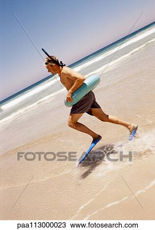 Man in inner tube and snorkeling gear running at the beach. View Large Photo Image Stock Image - Man in inner tube and snorkeling gear running at the beach.. Fotosearch